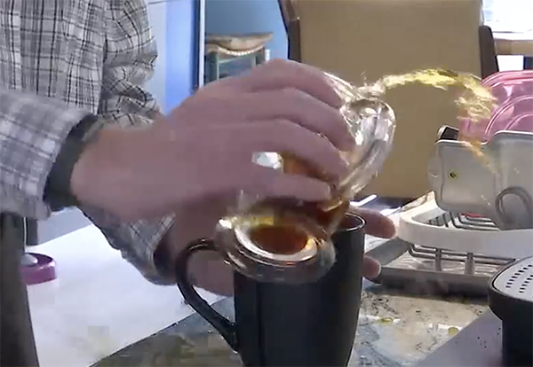 A shaking hand pouring coffee