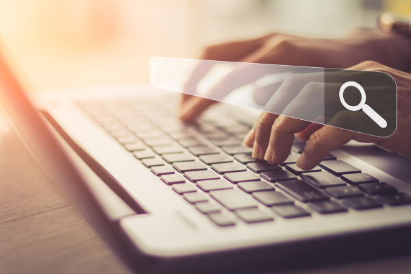 Hands typing on a keyboard with a search bar.