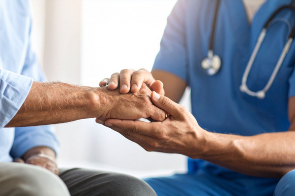 A medical provider holds a patient's hand in support and comfort.