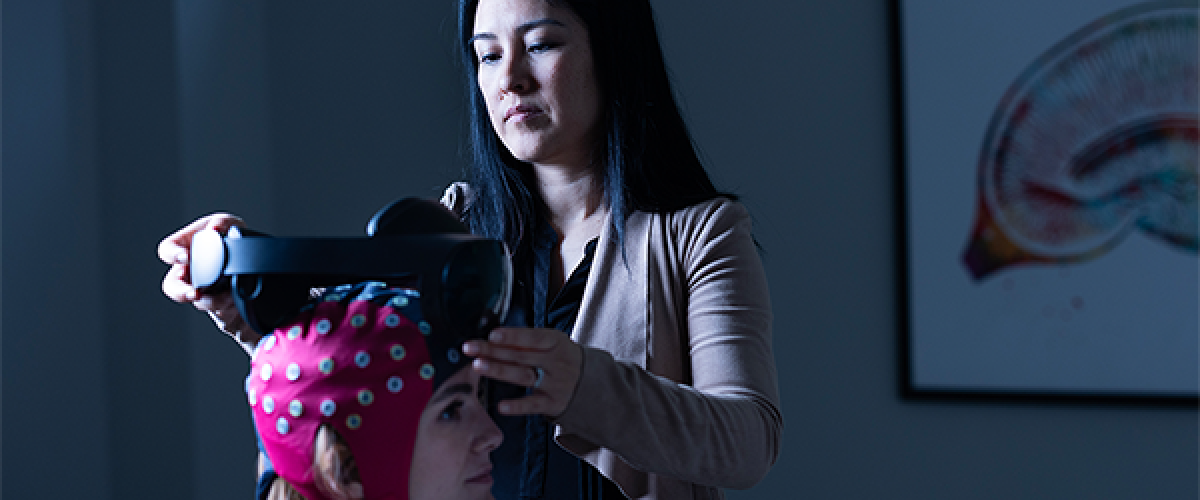 Nanthia Suthana fitting a brain imaging cap on a woman's head