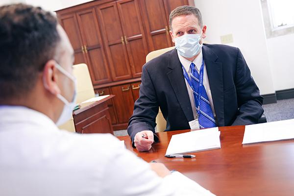 Gerry Grant sits across a table from Duke neurosurgeon Muhammad Abd-El-Barr as the converse