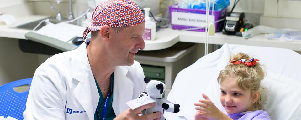 Dr. Grant talks to a young patient at bedside